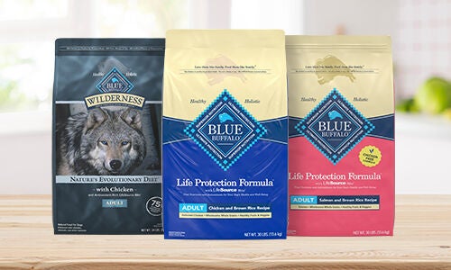 Three bags of dry dog food, one blue, one pink, one with a wolf on it